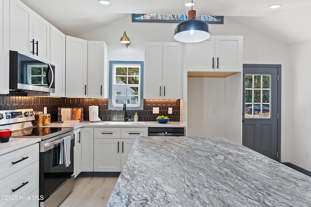 kitchen with lofted ceiling, a sink, backsplash, and appliances with stainless steel finishes