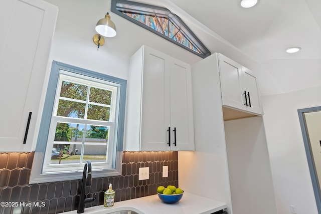 interior space with white cabinets, light countertops, decorative backsplash, and a sink