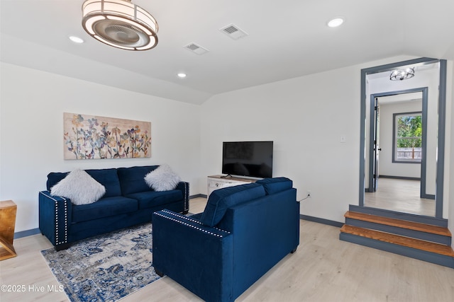 living room with vaulted ceiling, visible vents, light wood finished floors, and baseboards