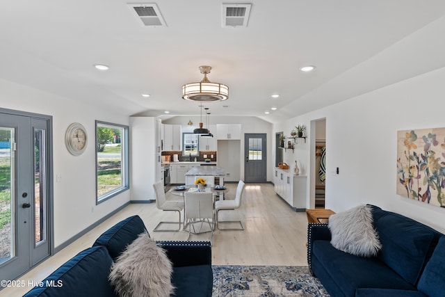 living room with lofted ceiling, visible vents, and a healthy amount of sunlight