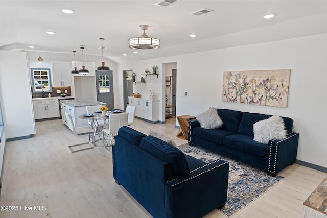 living room with baseboards, light wood-style flooring, visible vents, and recessed lighting