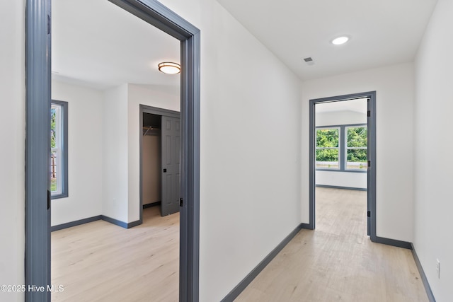 corridor with visible vents, baseboards, and light wood-style floors