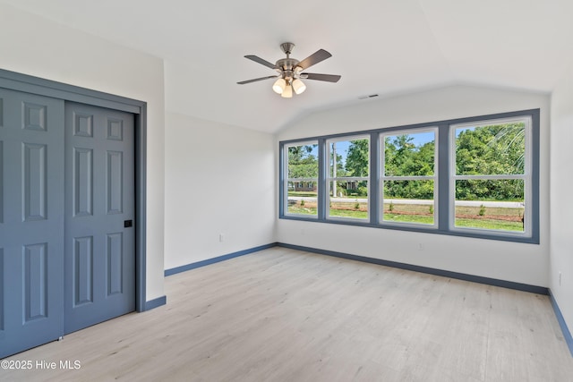 unfurnished bedroom featuring vaulted ceiling, light wood-style flooring, visible vents, and baseboards