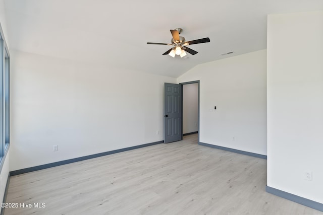 empty room with lofted ceiling, visible vents, a ceiling fan, light wood-style floors, and baseboards