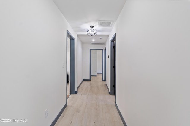 corridor featuring baseboards, visible vents, and light wood-type flooring