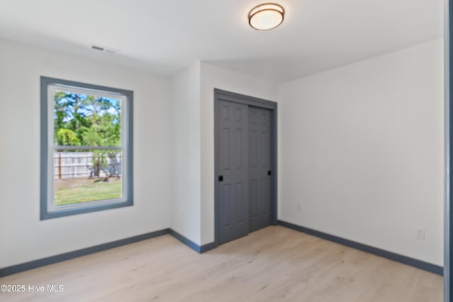 unfurnished bedroom with light wood finished floors, baseboards, a closet, and visible vents