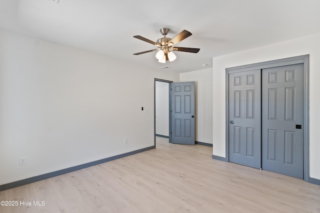 unfurnished bedroom with light wood-style floors, a closet, a ceiling fan, and baseboards