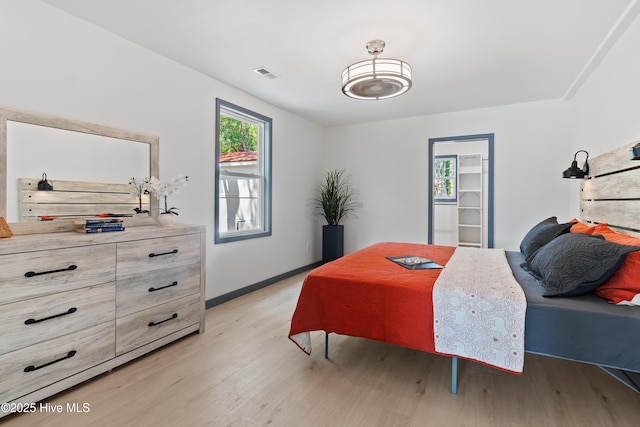 bedroom with baseboards, multiple windows, light wood-style floors, and visible vents