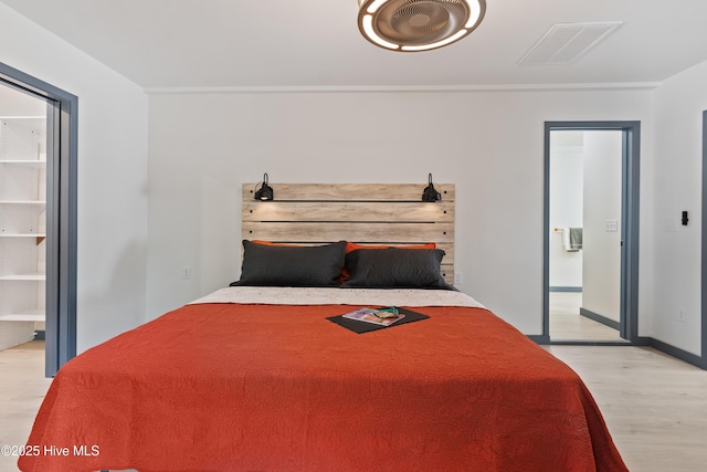bedroom featuring light wood-style floors, visible vents, and ensuite bathroom