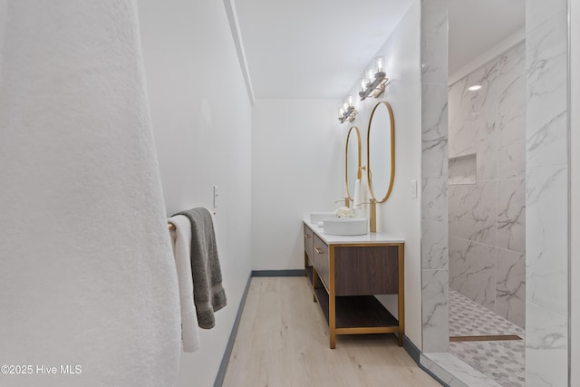 bathroom featuring vanity, wood finished floors, and a marble finish shower
