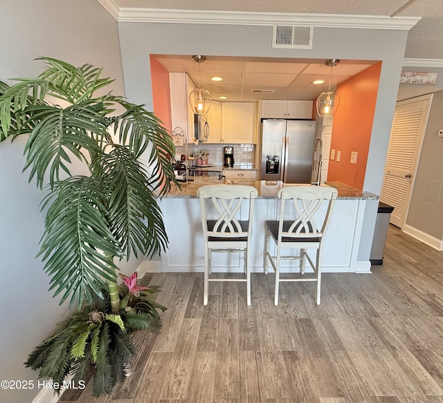 2000 New River Inlet Rd Unit 2602, North Topsail Beach, NC 28460 - kitchen with crown molding, light wood finished floors, visible vents, a peninsula, and appliances with stainless steel finishes