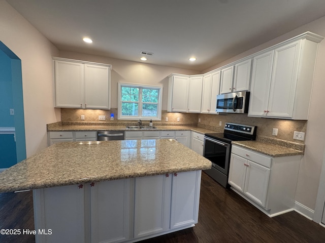 427 Wolfe Ln, Hubert, NC 28539 - kitchen with stainless steel appliances, a center island, dark wood-style floors, white cabinetry, and decorative backsplash