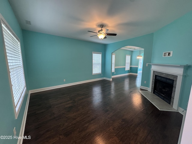 427 Wolfe Ln, Hubert, NC 28539 - unfurnished living room with dark wood-type flooring, a tile fireplace, a ceiling fan, and arched walkways