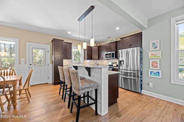 214 Green Trees Dr, New Bern, NC 28560 - kitchen featuring dark brown cabinetry, a breakfast bar area, appliances with stainless steel finishes, tasteful backsplash, and light wood-style floors