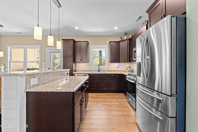 214 Green Trees Dr, New Bern, NC 28560 - kitchen with dark brown cabinets, light wood-style flooring, a center island, stainless steel appliances, and visible vents