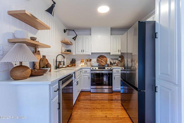 kitchen featuring premium range hood, open shelves, a sink, stainless steel appliances, and light countertops