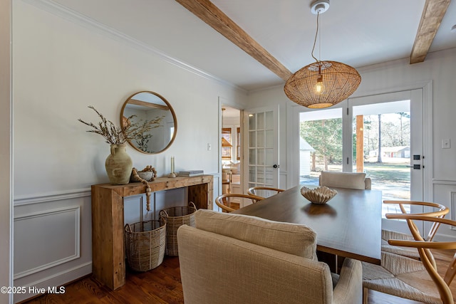 dining room with beam ceiling, a decorative wall, wainscoting, and wood finished floors