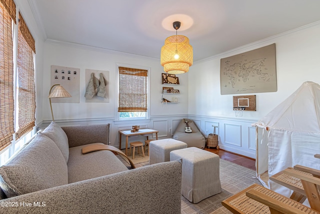 living room featuring wainscoting, wood finished floors, crown molding, and a decorative wall