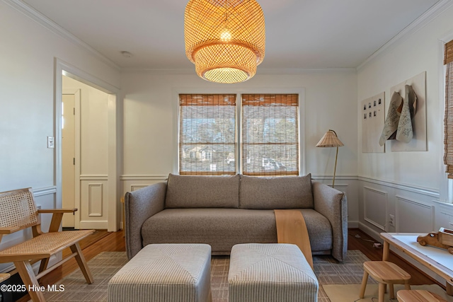 living area with a decorative wall, a wainscoted wall, crown molding, and wood finished floors