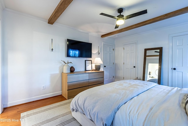 bedroom featuring beam ceiling, light wood-style floors, baseboards, and ornamental molding