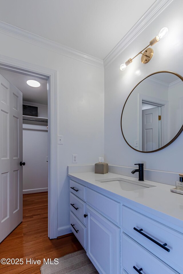 bathroom featuring baseboards, vanity, wood finished floors, and crown molding