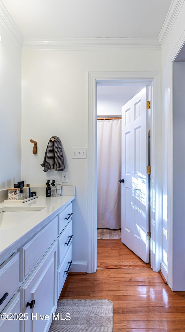 bathroom featuring vanity, hardwood / wood-style flooring, and ornamental molding
