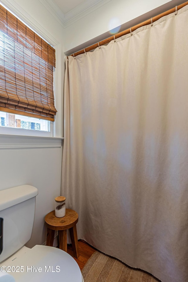 bathroom featuring toilet, wood finished floors, and ornamental molding