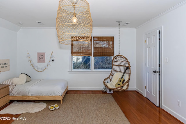 bedroom with crown molding, wood finished floors, visible vents, and baseboards