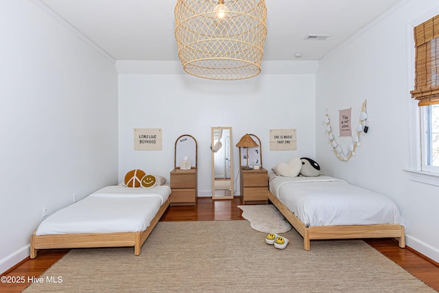 bedroom with visible vents, wood finished floors, and crown molding