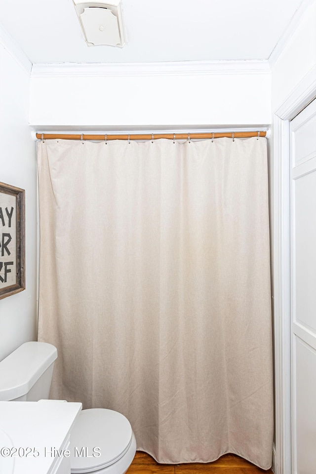 bathroom featuring toilet, wood finished floors, and ornamental molding