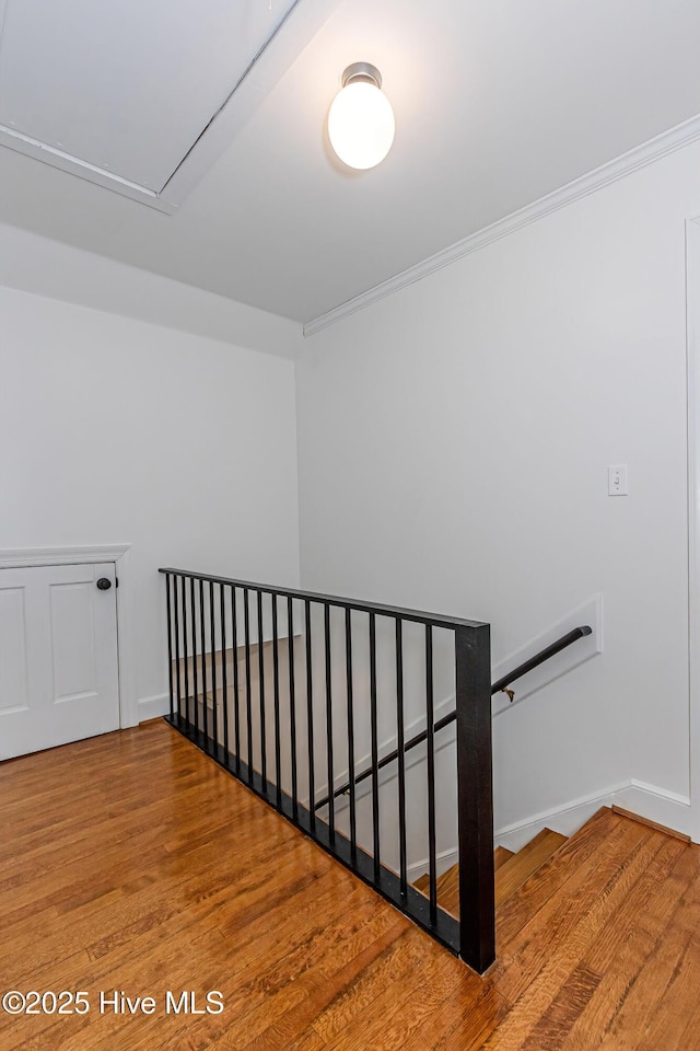 stairway with attic access, crown molding, baseboards, and wood finished floors