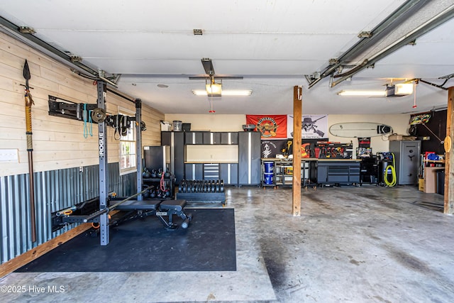 garage featuring wooden walls, a workshop area, and a garage door opener