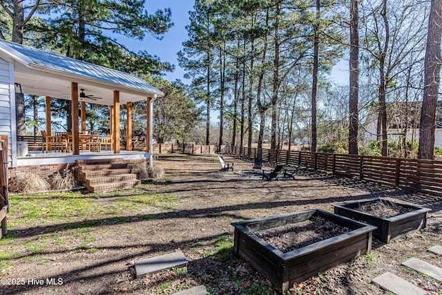 view of yard featuring a vegetable garden, ceiling fan, and fence