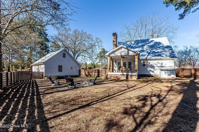 rear view of house featuring ceiling fan, a chimney, and fence