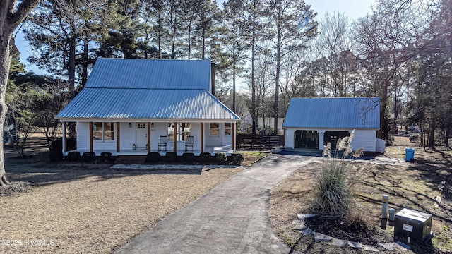 view of front of property with an outbuilding, fence, covered porch, metal roof, and a garage