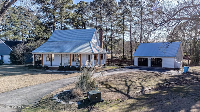 view of front of house with metal roof, a porch, a chimney, and fence