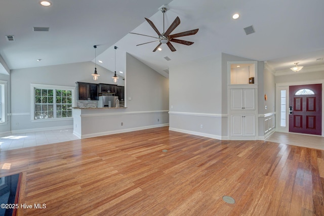unfurnished living room featuring light wood-style flooring, visible vents, vaulted ceiling, and a ceiling fan