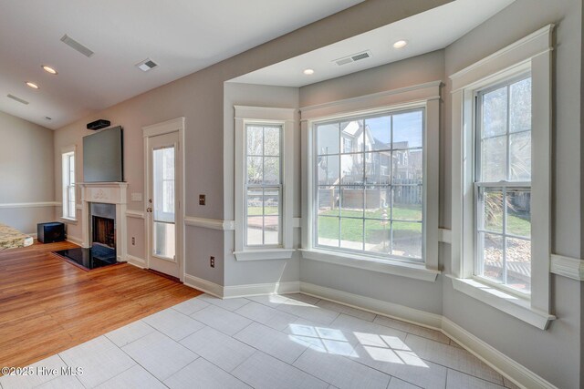 doorway to outside featuring a fireplace, a wealth of natural light, and visible vents