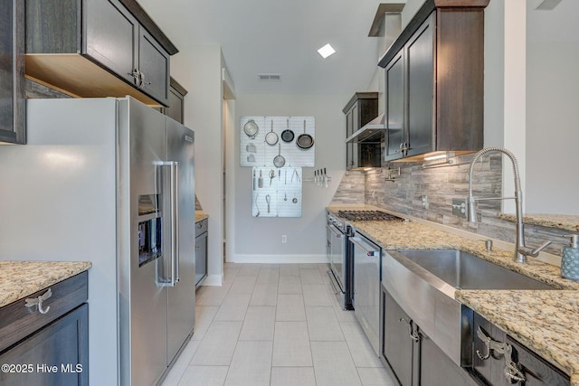 kitchen featuring light stone counters, visible vents, a sink, tasteful backsplash, and appliances with stainless steel finishes