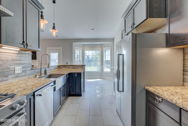 kitchen featuring a sink, stainless steel appliances, backsplash, under cabinet range hood, and light stone countertops