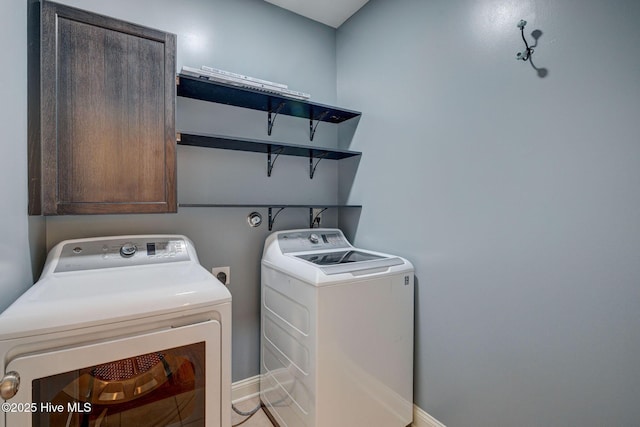 clothes washing area with cabinet space, independent washer and dryer, and baseboards