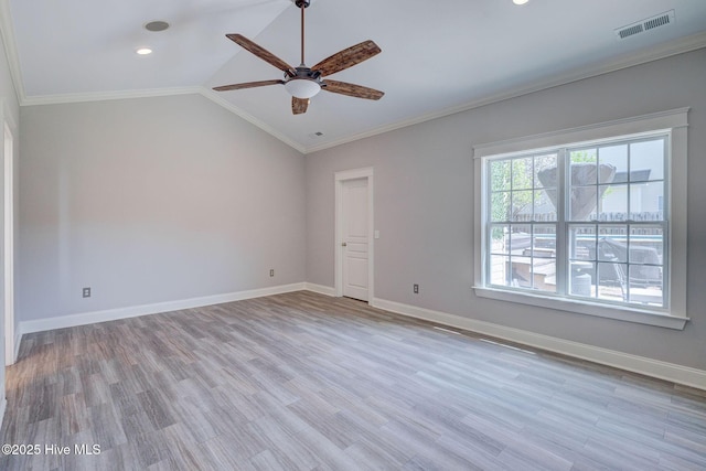 empty room featuring lofted ceiling, wood finished floors, visible vents, a ceiling fan, and ornamental molding