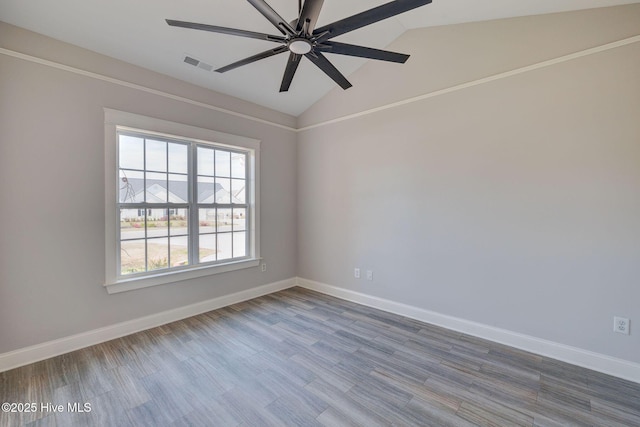 spare room featuring baseboards, visible vents, lofted ceiling, a ceiling fan, and wood finished floors
