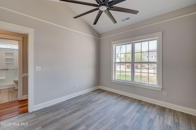 empty room with a ceiling fan, wood finished floors, baseboards, lofted ceiling, and visible vents