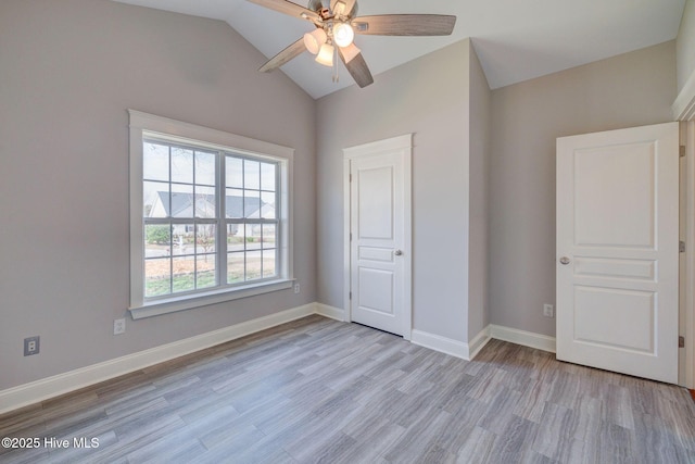 unfurnished bedroom with baseboards, vaulted ceiling, a ceiling fan, and light wood-type flooring