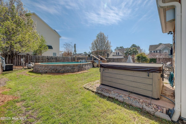 view of yard with a fenced backyard, a fenced in pool, and a hot tub
