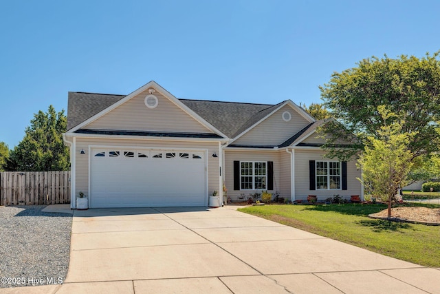 view of front of home with concrete driveway, fence, a front yard, and a garage