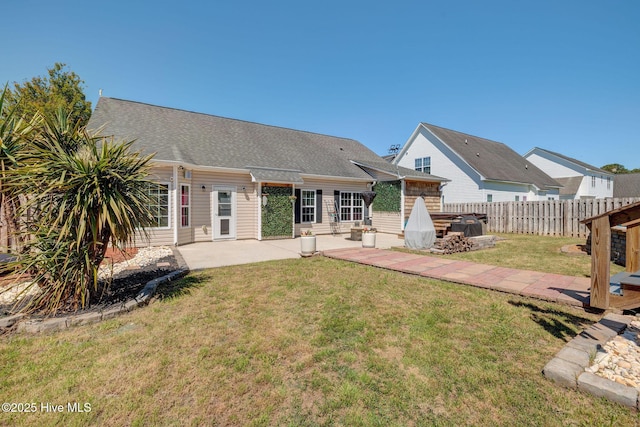 rear view of property with fence, a yard, a patio, and a shingled roof
