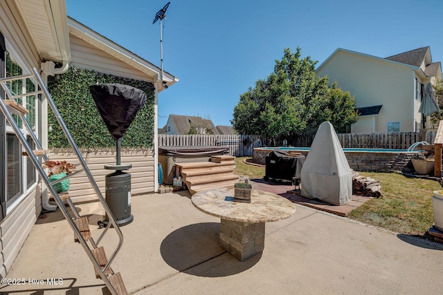 view of patio / terrace featuring a hot tub, a fenced backyard, and a swimming pool