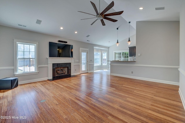 unfurnished living room featuring visible vents, a ceiling fan, and a wealth of natural light